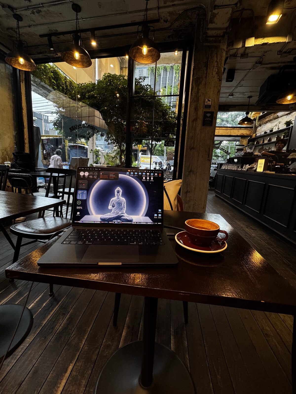 Laptop and a coffee on a dark wooden table in a Bangkok café